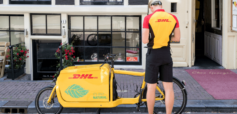 Carteiro da DHL em frente a bicicleta.