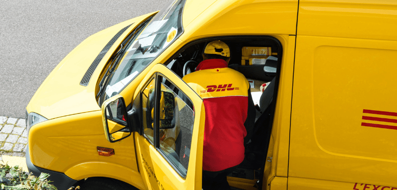 Entregador uniformizado da DHL, dentro de carro de entrega.