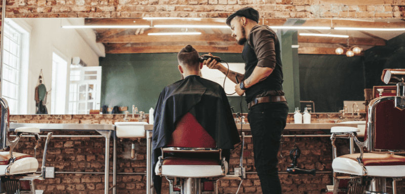 Barbeiro fazendo corte de cabelo.