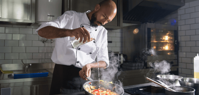 Cozinheiro profissional preparando refeição.